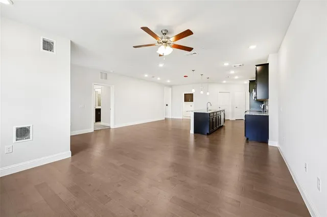 a view of a livingroom with a kitchen island wooden floor and a ceiling fan
