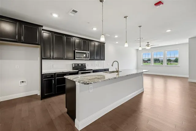 a large kitchen with stainless steel appliances granite countertop a stove a sink and a refrigerator
