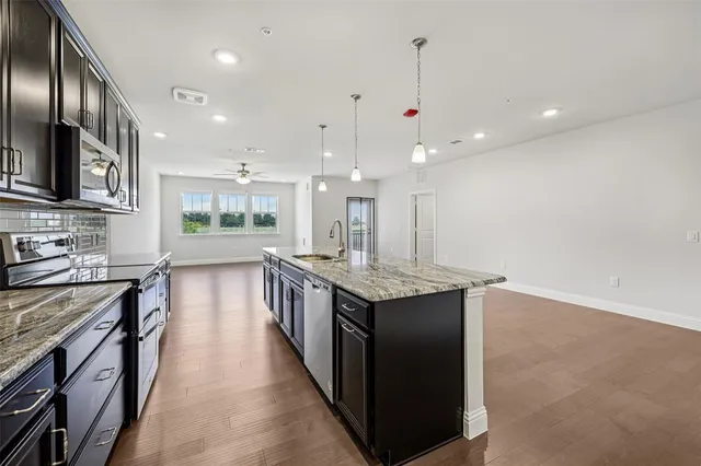 a kitchen with stainless steel appliances granite countertop a kitchen island a stove and a sink