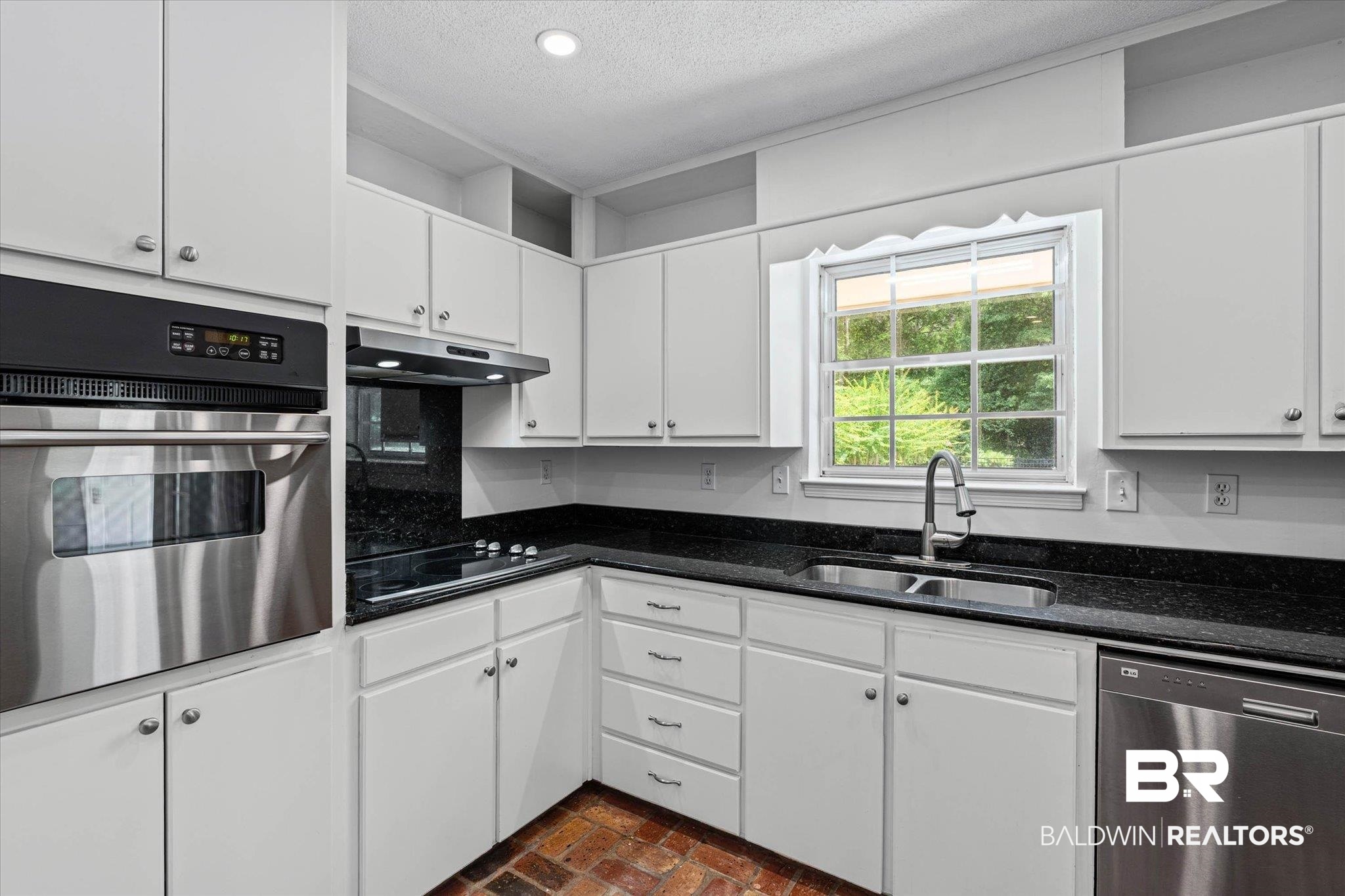 8301 Fordham Road Mobile, AL 36619 - Photo 11 of 57 Kitchen featuring white cabinetry, black countertops, stainless steel appliances, and brick-finish flooring