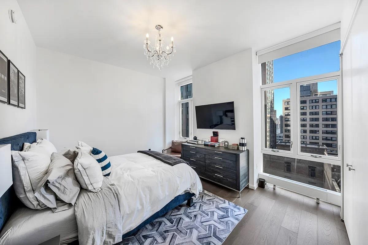 5 Beekman Street, Unit 18C Manhattan, NY 10038 - Photo 3 of 21 a bedroom with bed and flat tv with wooden floor