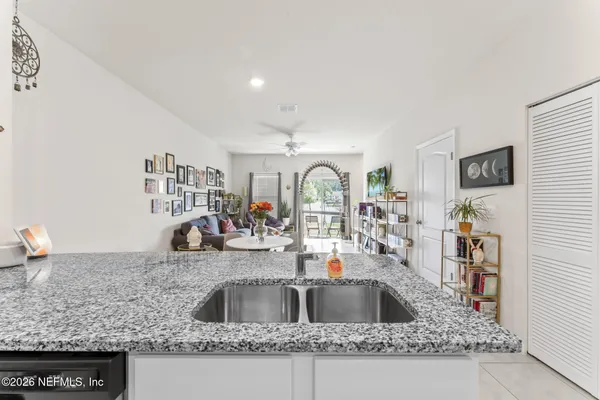a kitchen with sink a granite counter top and a view of living room