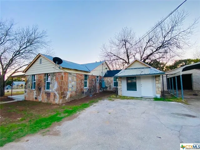 a view of a house with a yard and large tree