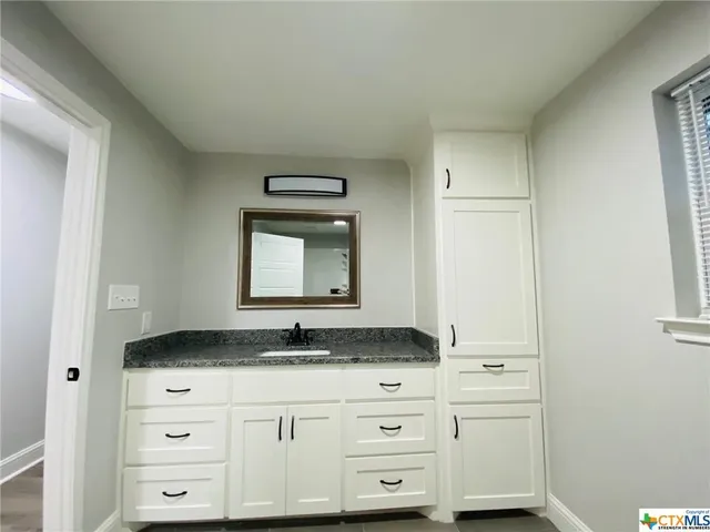 a bathroom with a granite countertop sink and a mirror