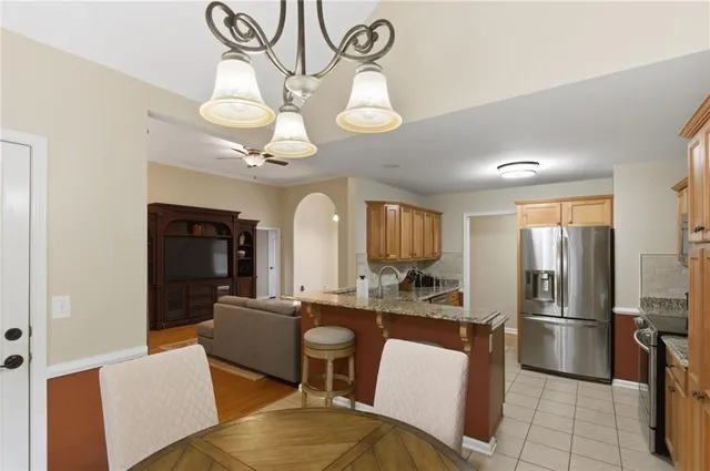 a living room with stainless steel appliances furniture a fireplace and a open kitchen view