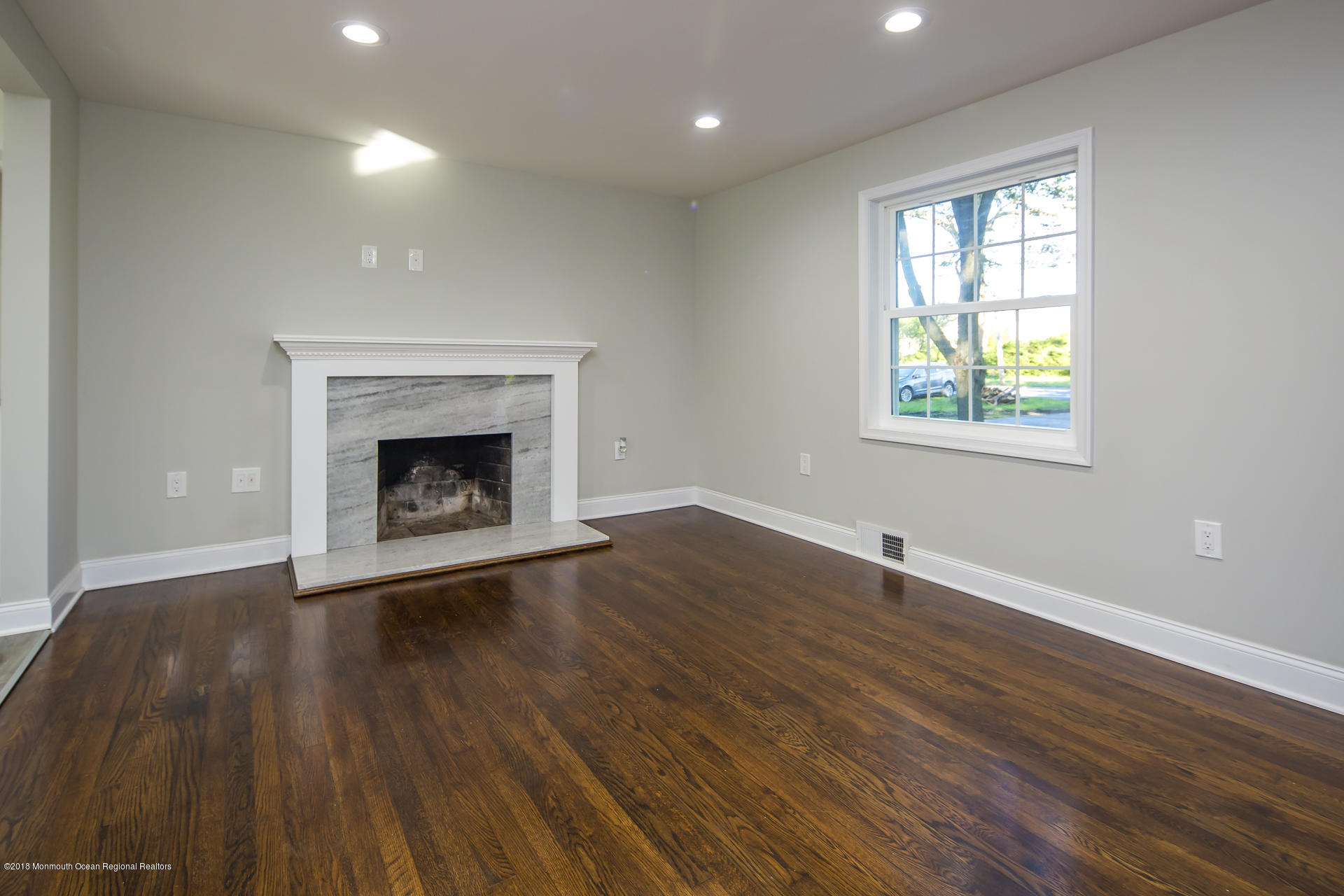 584 Colts Neck Road Freehold, NJ 07728 - Photo 4 of 29 an empty room with wooden floor a fireplace and windows