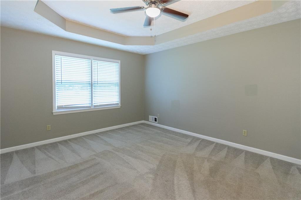 374 McGiboney Road Covington, GA 30016 - Photo 18 of 29 an empty room with a chandelier fan and windows