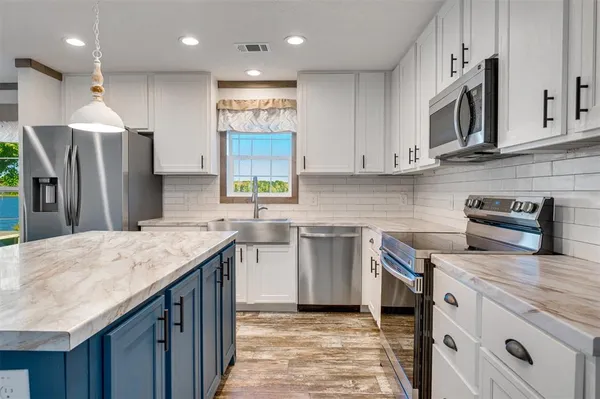a kitchen with stainless steel appliances granite countertop a sink a stove and a refrigerator