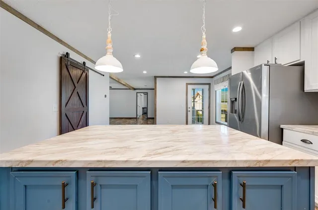 a room with kitchen island a refrigerator wooden floor and a sink