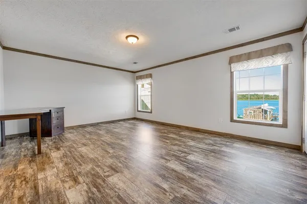 a view of an empty room with window and wooden floor