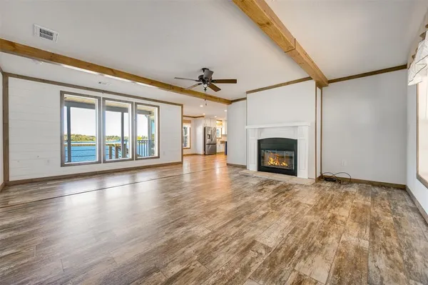 an empty room with wooden floor fireplace and windows