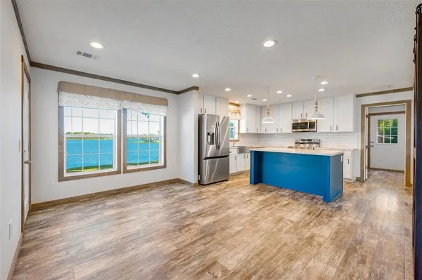 a large kitchen with stainless steel appliances granite countertop a stove a refrigerator a sink dishwasher and a large countertops with wooden floor