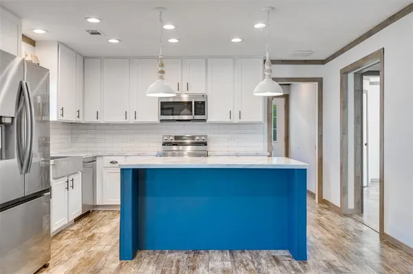 a kitchen with kitchen island granite countertop a sink cabinets and stainless steel appliances