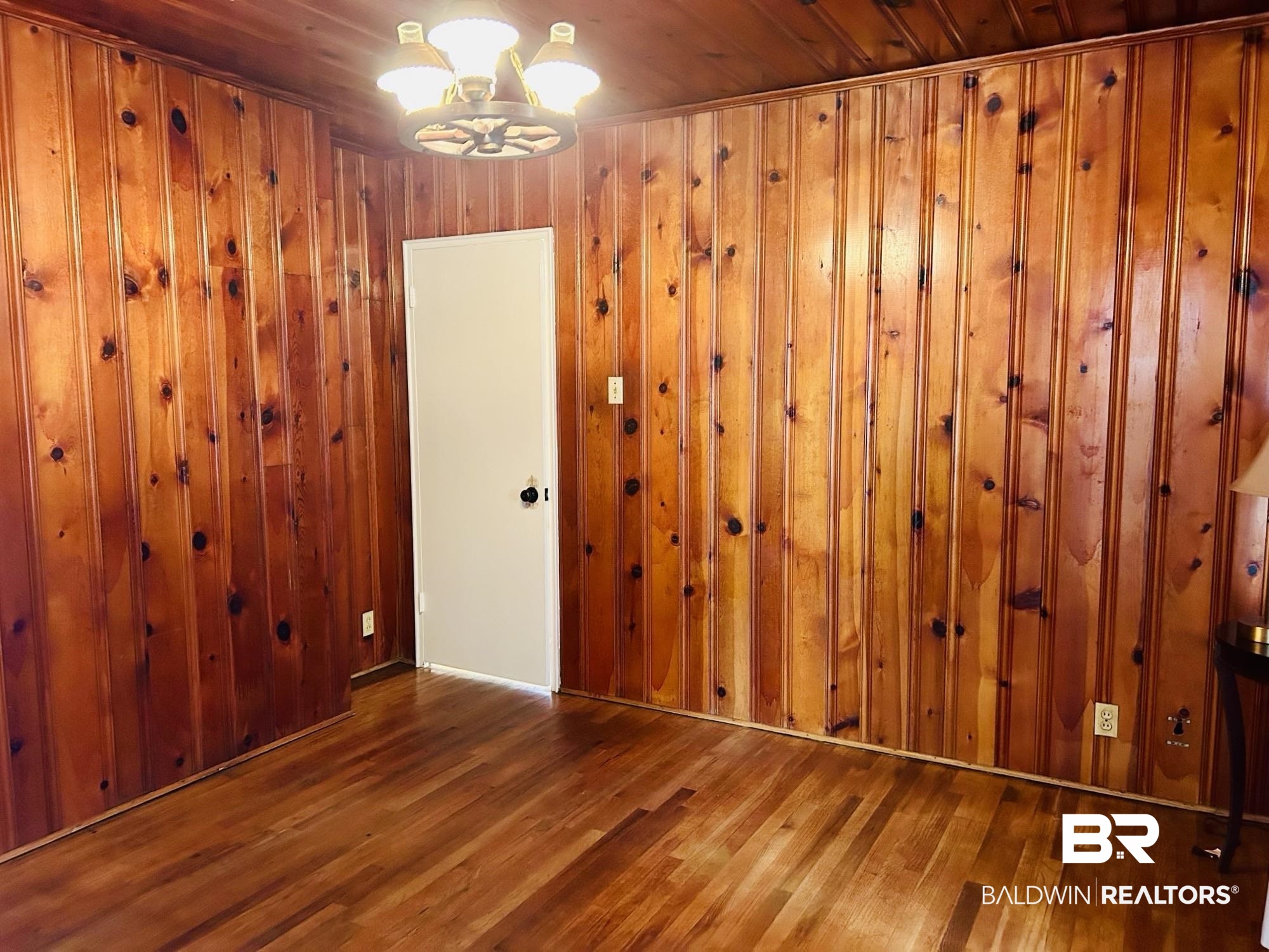 94 Diamond Street Mobile, AL 36611 - Photo 20 of 30 Unfurnished room with wood-type flooring, wooden walls, and a chandelier