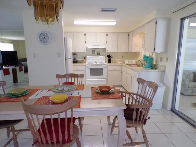 a kitchen with granite countertop a dining table chairs and a stove top oven