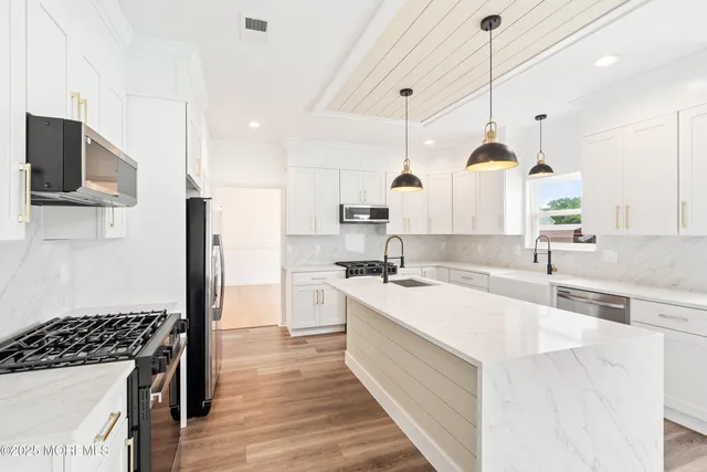 a kitchen with kitchen island granite countertop a sink a counter space appliances and cabinets