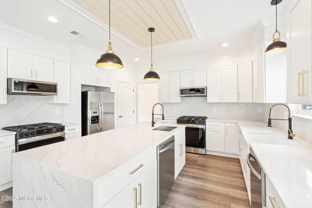 a kitchen with stainless steel appliances a sink a stove a refrigerator cabinets and a window