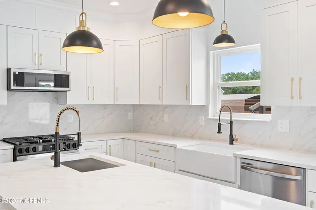 a kitchen with stainless steel appliances kitchen island a white cabinets and a wooden floor