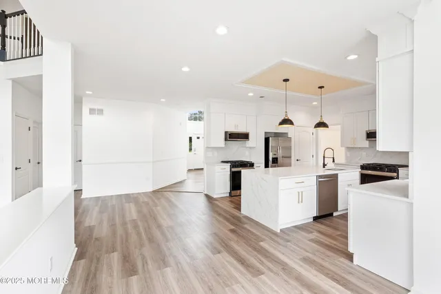 a large white kitchen with wooden floor and a large window