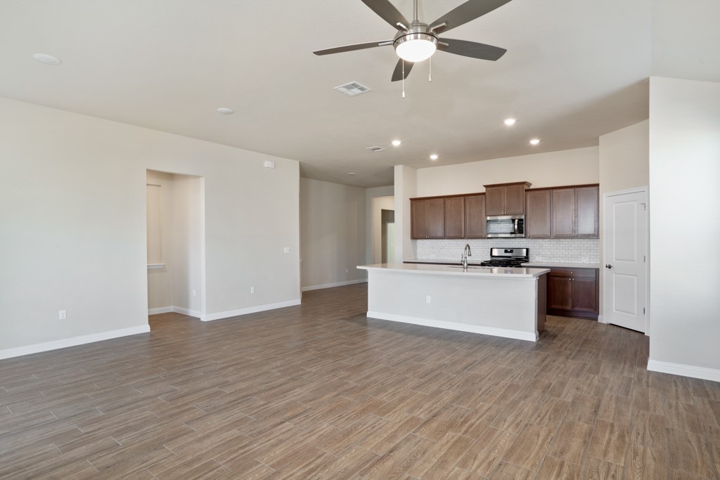 8202 Dampton Lane Austin, TX 78744 - Photo 11 of 25 a large kitchen with stainless steel appliances kitchen island a large counter top and wooden floors