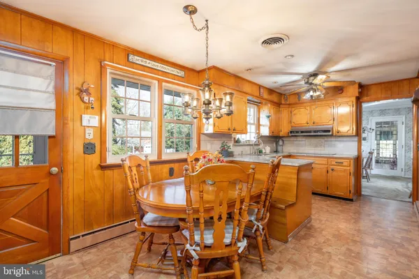 a dining hall with stainless steel appliances granite countertop a stove and a view of living room