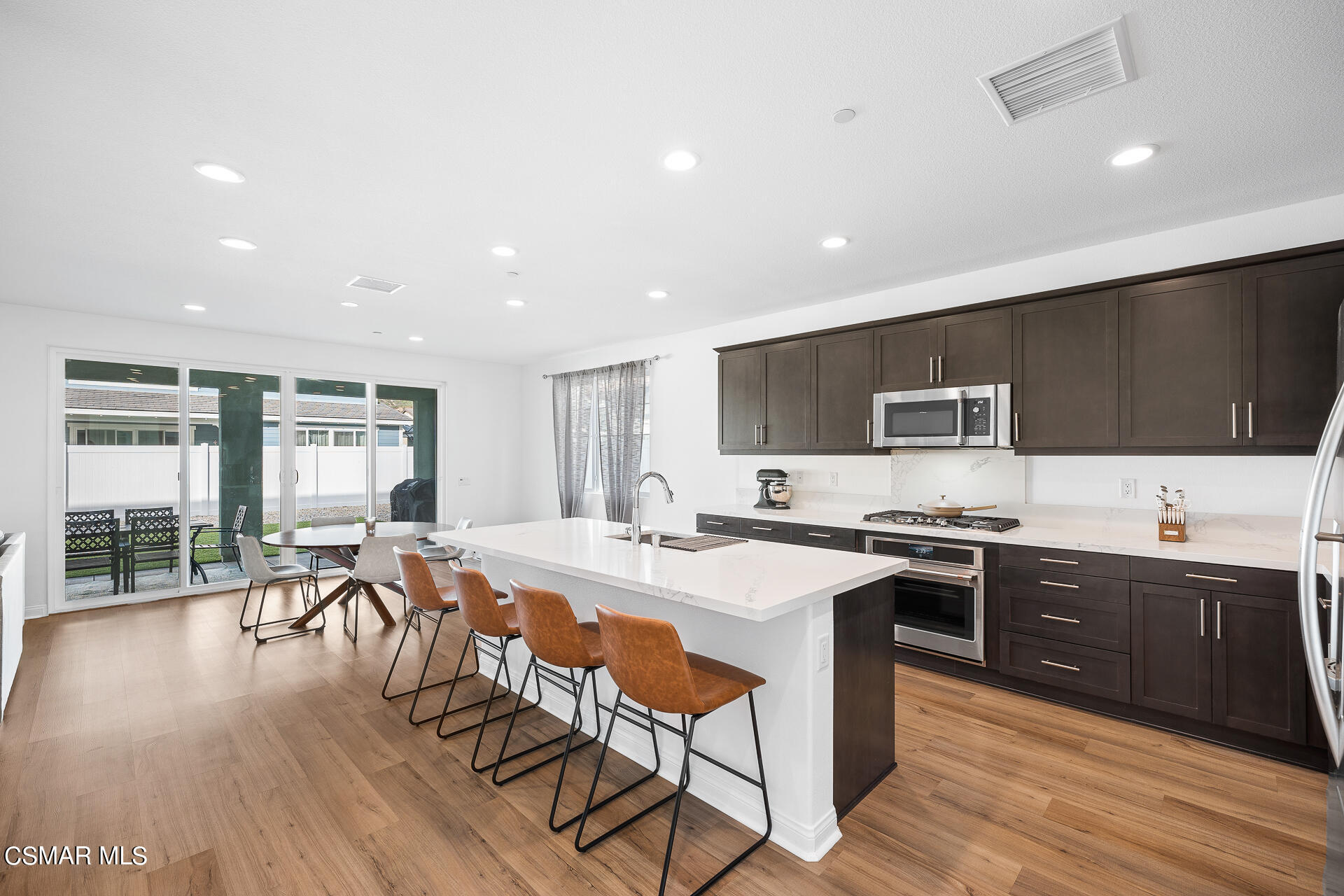 369 Rose Street Fillmore, CA 93015 - Photo 9 of 52 a kitchen with stainless steel appliances granite countertop a stove top oven a sink dishwasher a dining table and chairs with wooden floor