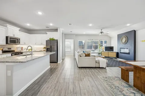 a large white kitchen with kitchen island a large counter top space stainless steel appliances and cabinets