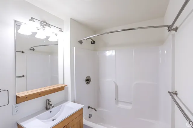 a bathroom with a tub sink shower and mirror