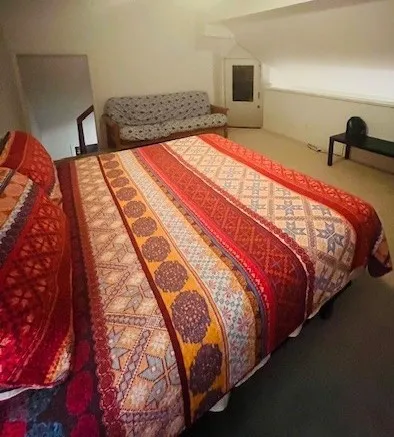 a bed sitting in a bedroom next to a window with a bookshelf