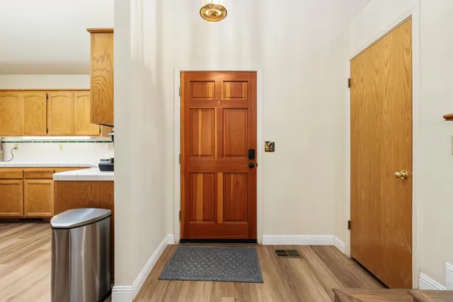 a view of a hallway with wooden floor and a bathroom