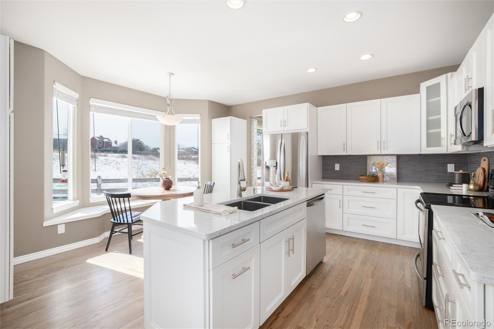 9486 South Autumn Ash Place Highlands Ranch, CO 80126 - Photo 13 of 50 a kitchen with stainless steel appliances granite countertop a stove top oven a sink dishwasher and white cabinets with wooden floor