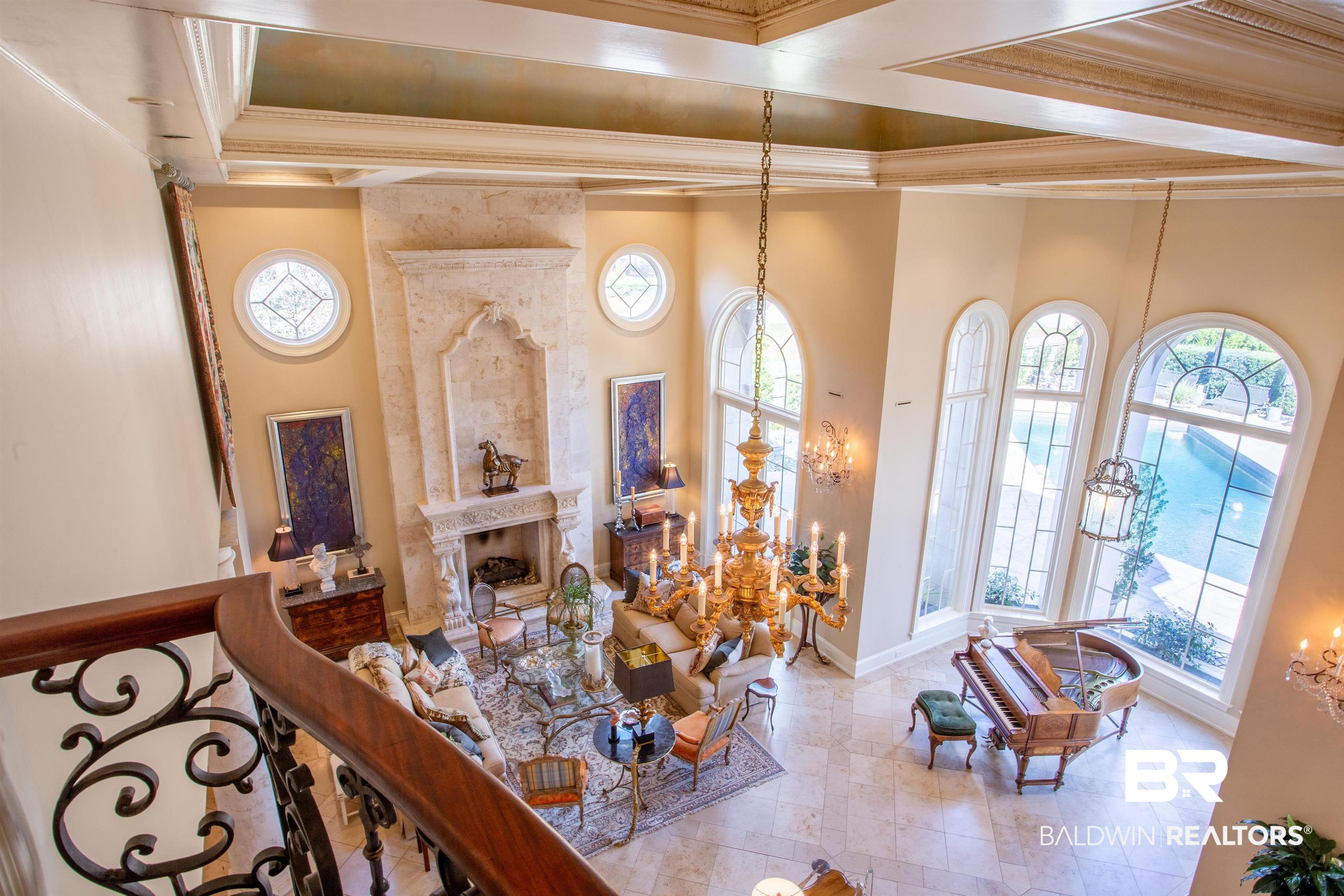 150 Austill Avenue Mobile, AL 36608 - Photo 26 of 39 Two-story living area featuring a decorative stone fireplace, arched windows, and tiled flooring