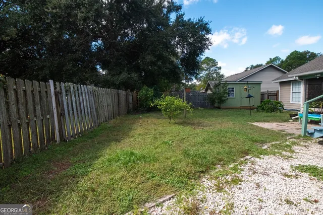 a view of a backyard with plants and large trees