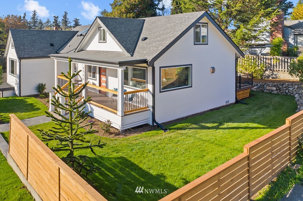 4906 Southwest Hinds Street Seattle, WA 98116 - Photo 7 of 40 a view of a white house with large windows next to a yard