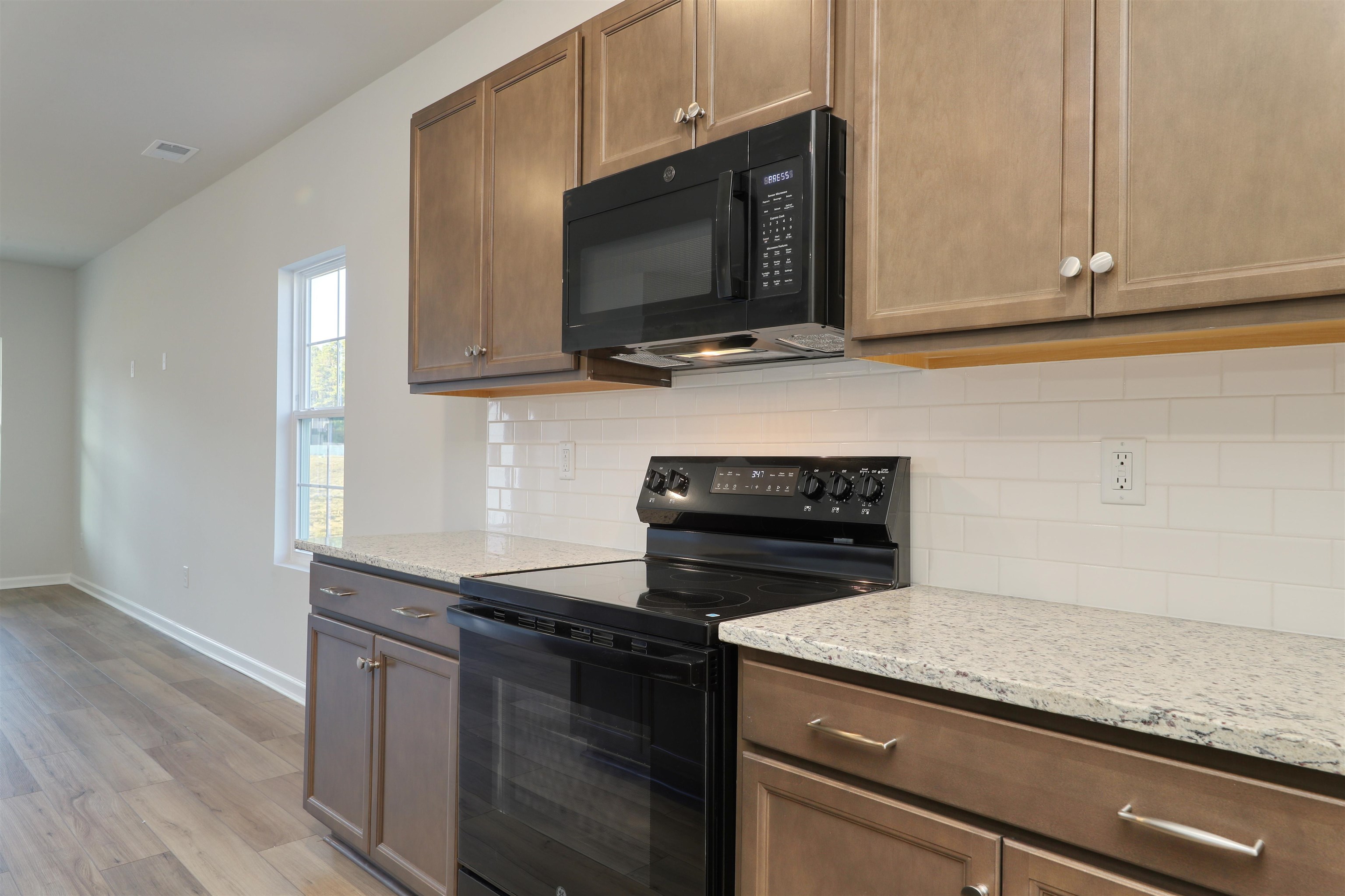 3431 Logan Street Conway, SC 29526 - Photo 11 of 31 Kitchen with black appliances, light stone counters, backsplash, and light wood finished floors