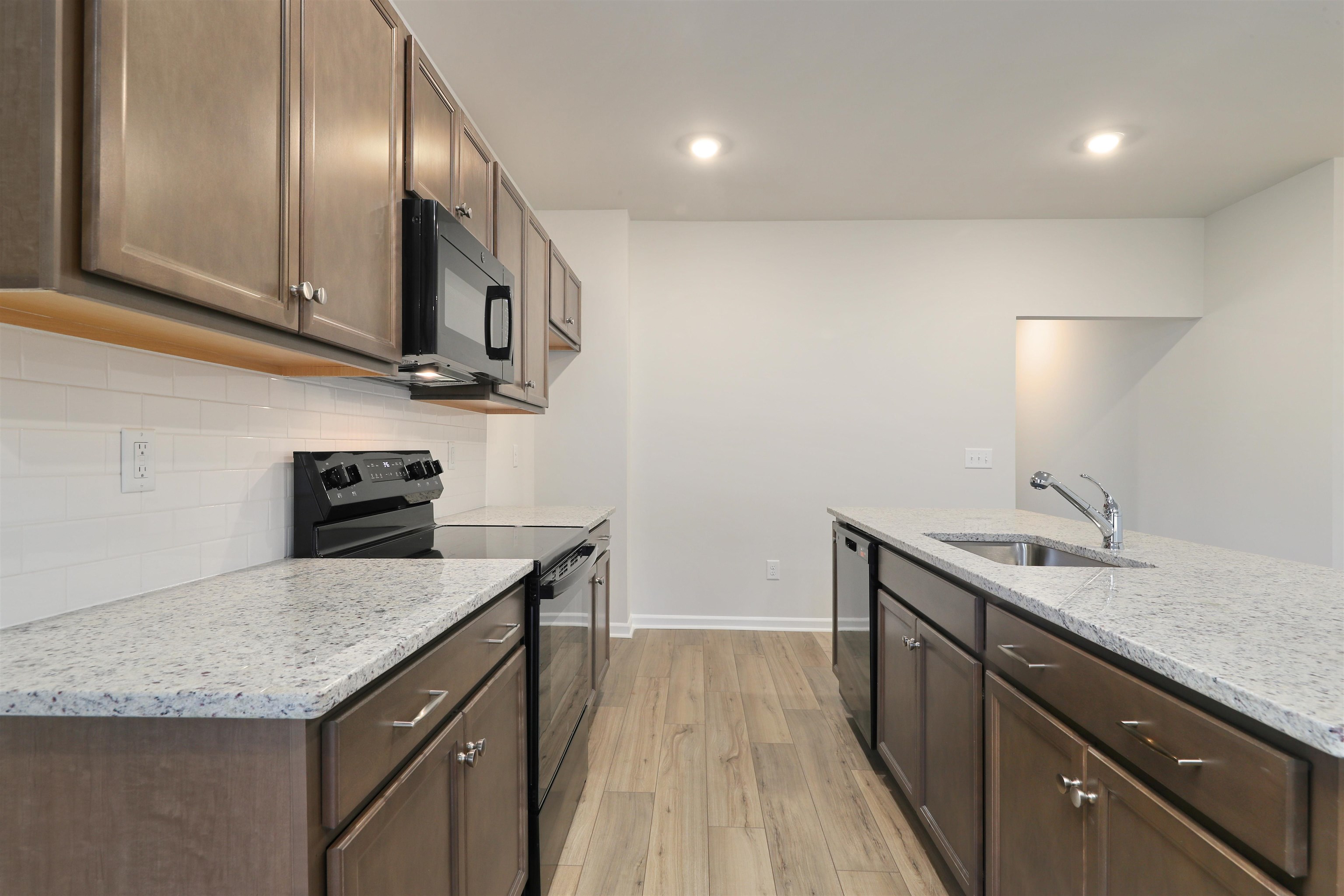 3431 Logan Street Conway, SC 29526 - Photo 10 of 31 Kitchen with black appliances, light wood-type flooring, dark brown cabinetry, light stone counters, and recessed lighting