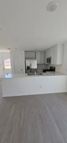 a view of a kitchen with a sink and dishwasher a stove top oven with wooden floor