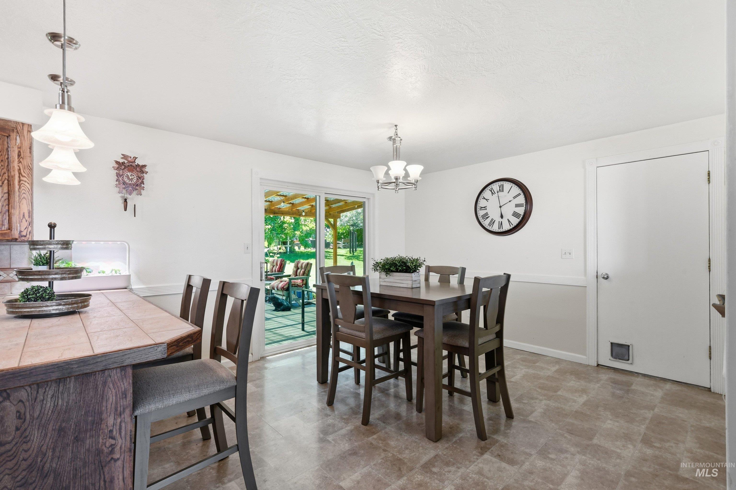 15095 David Street Caldwell, ID 83607 - Photo 13 of 39 Dining area featuring a sliding glass door to the patio, overhead chandelier, and tile-look flooring