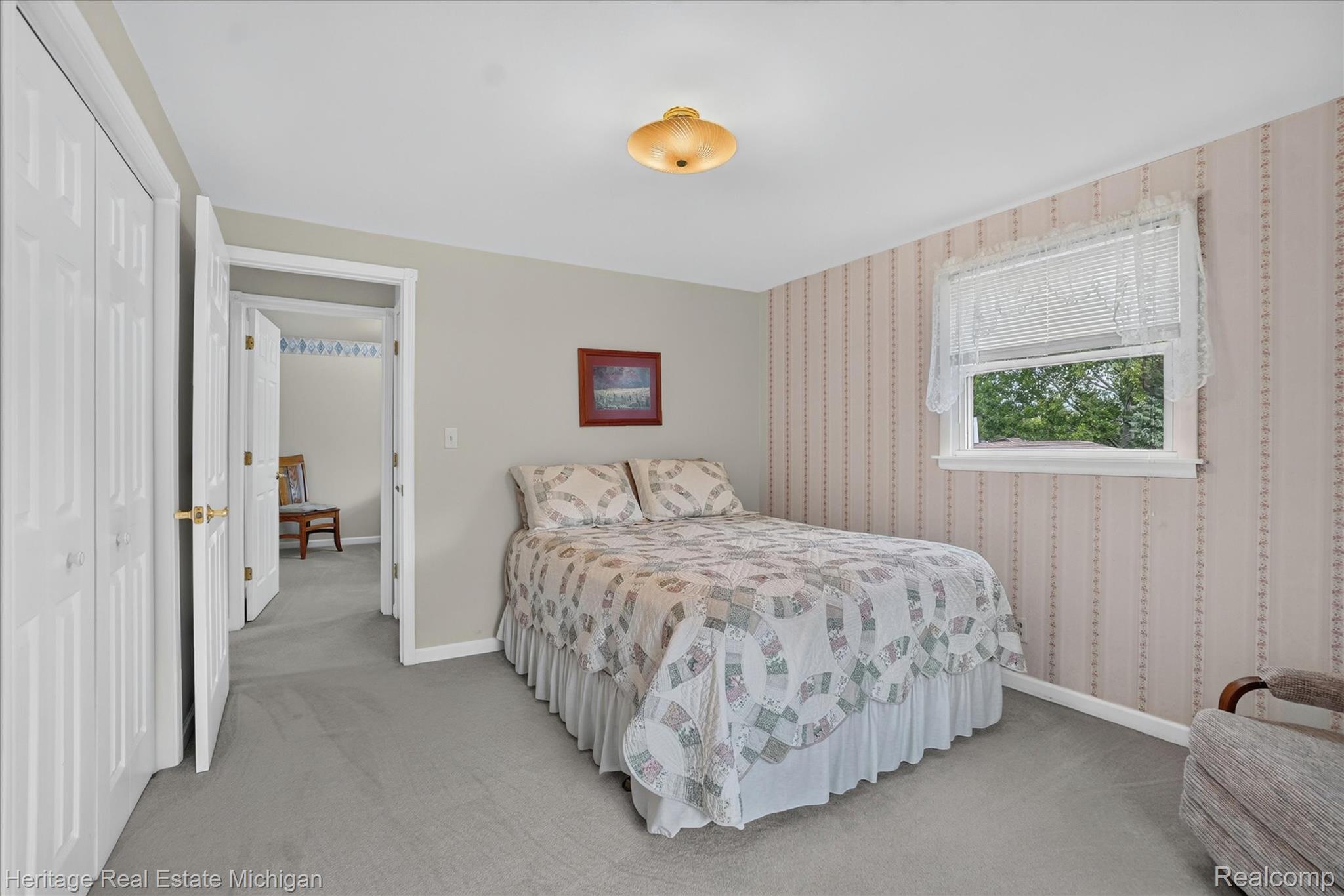 14038 North Hogan Road Linden, MI 48451 - Photo 33 of 53 Carpeted room featuring a window with white trim, a built-in ceiling light fixture, and two bi-fold closet doors with brass hardware