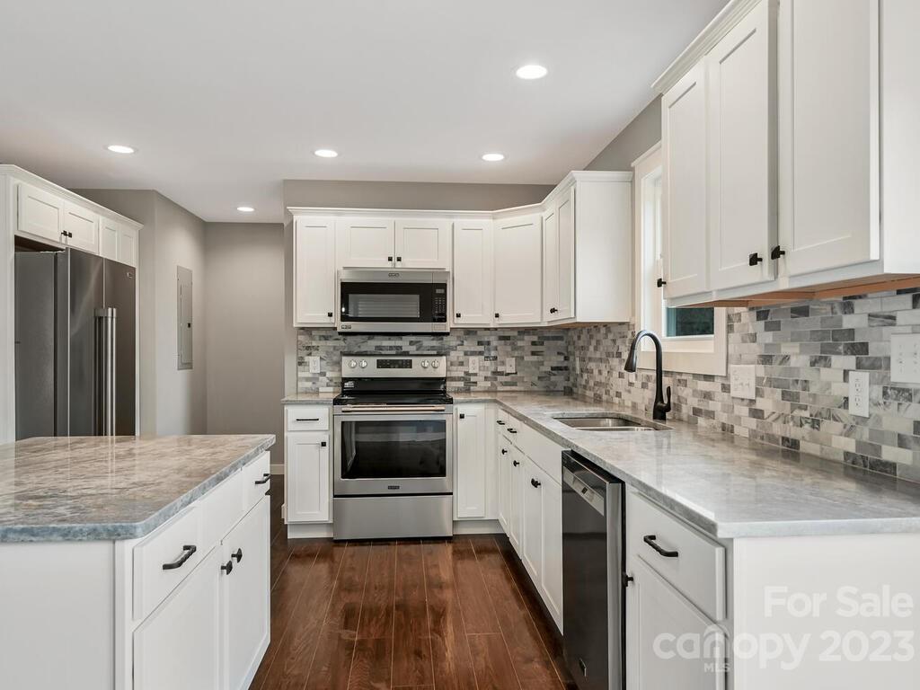 921 Newfound Road Leicester, NC 28748 - Photo 12 of 28 a kitchen with granite countertop white cabinets and stainless steel appliances