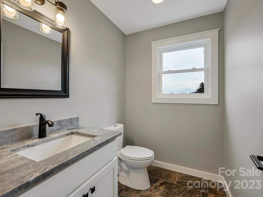 921 Newfound Road Leicester, NC 28748 - Photo 16 of 28 a bathroom with a granite countertop toilet sink and mirror