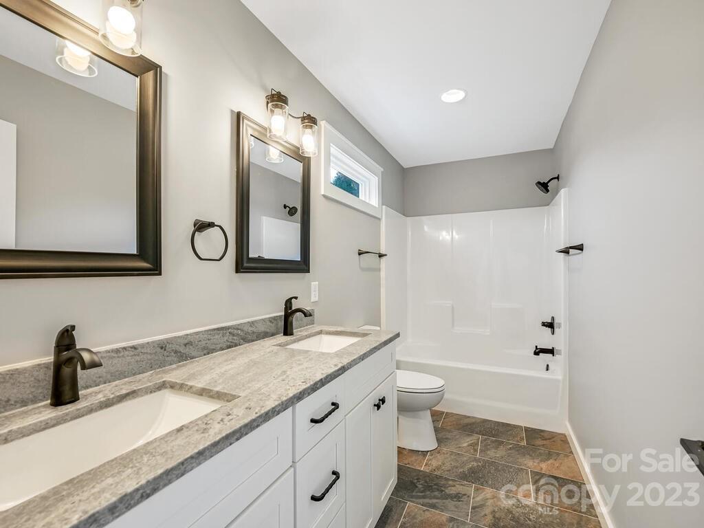 921 Newfound Road Leicester, NC 28748 - Photo 27 of 28 a bathroom with a granite countertop sink toilet and shower