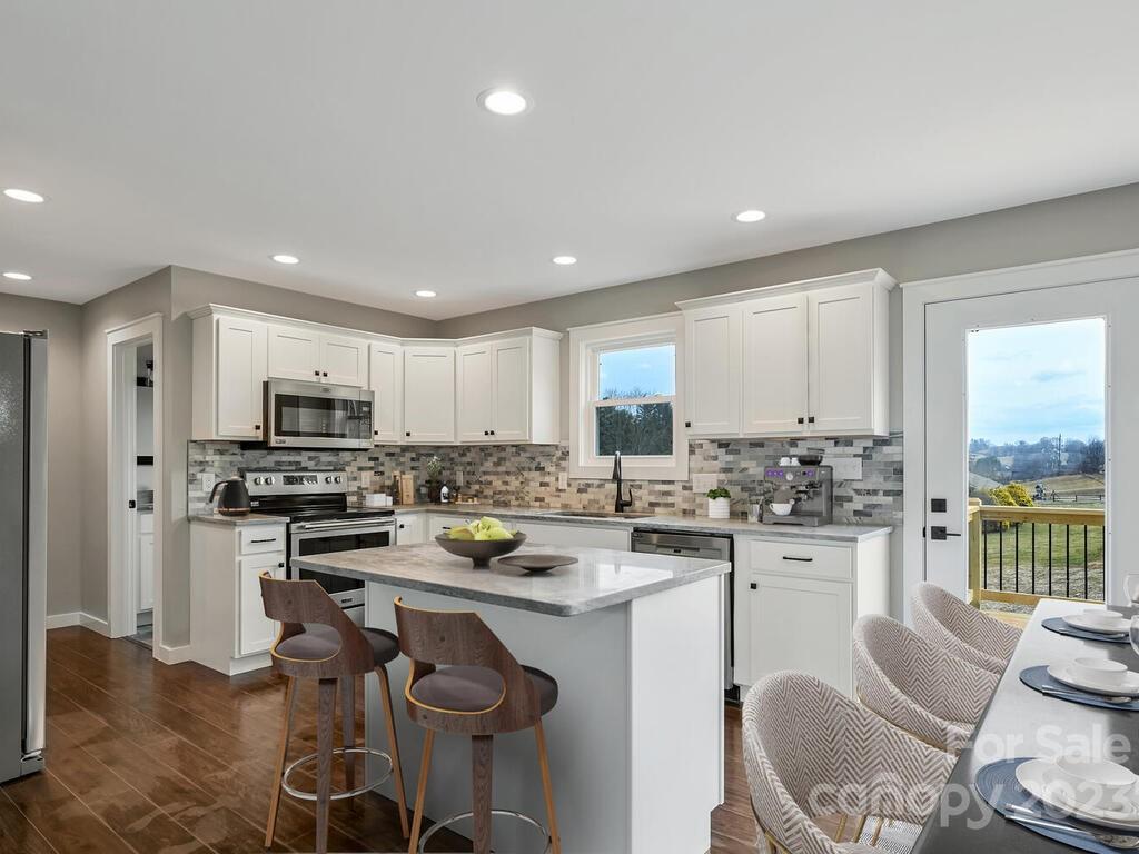 921 Newfound Road Leicester, NC 28748 - Photo 8 of 28 a kitchen with a sink a stove a refrigerator and white cabinets with wooden floor