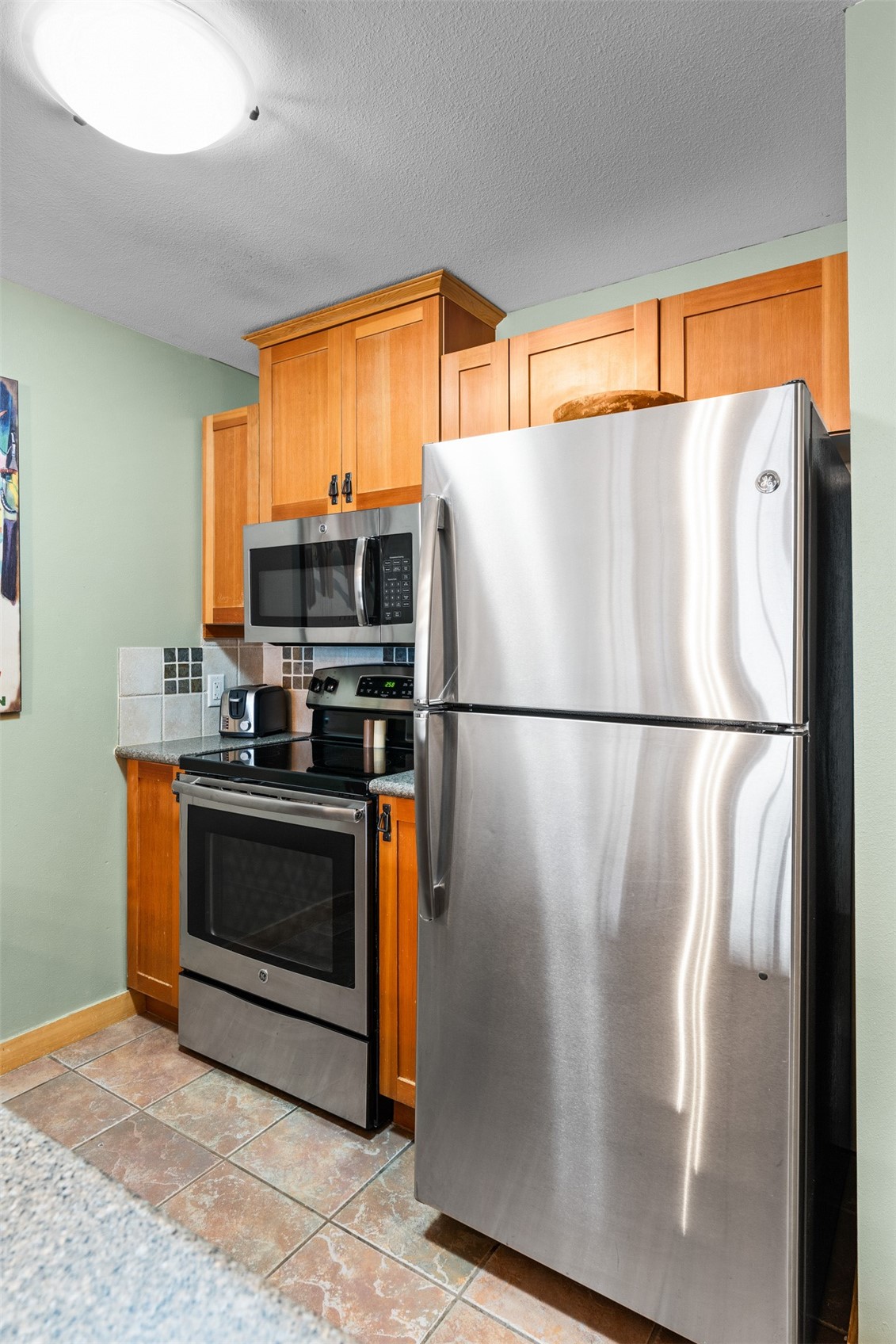 910 Copper Road, Unit 308 Frisco, CO 80443 - Photo 13 of 42 Kitchen with appliances with stainless steel, brown cabinets, and light tile patterned floors