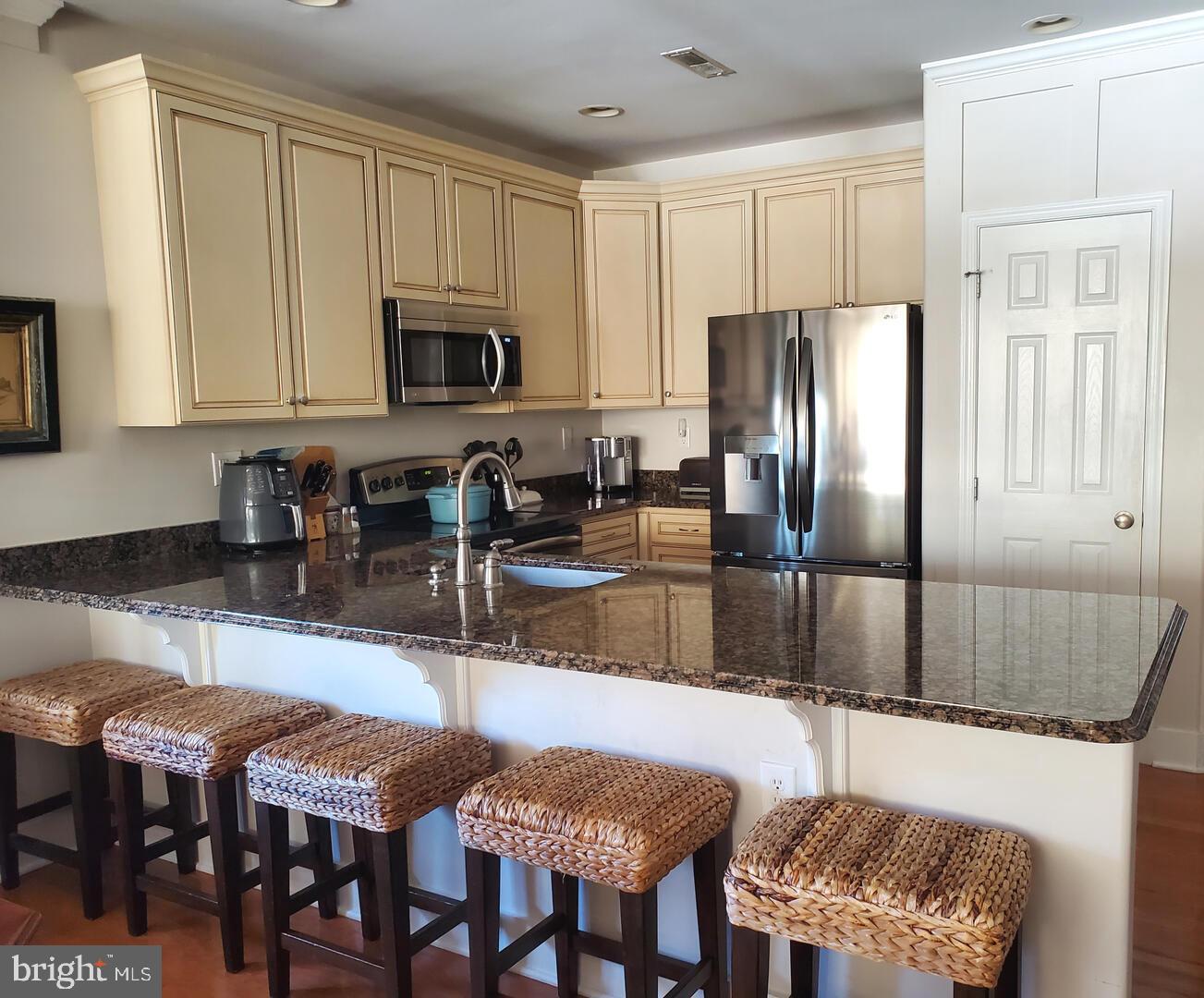 17432 Slipper Shell Way Lewes, DE 19958 - Photo 3 of 12 a kitchen with stainless steel appliances granite countertop a stove a sink a refrigerator a dining table and chairs