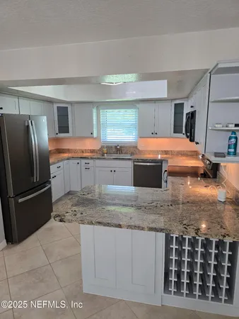 a kitchen with kitchen island granite countertop a sink and a refrigerator