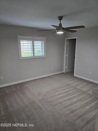 en empty room with windows and ceiling fan