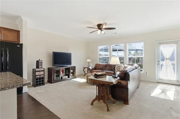 a living room with furniture a flat screen tv and a refrigerator
