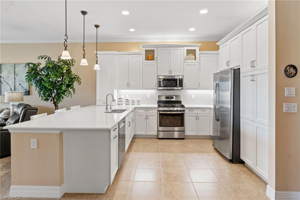 4339 Aurora Street Naples, FL 34119 - Photo 11 of 47 a kitchen with stainless steel appliances a refrigerator sink and stove