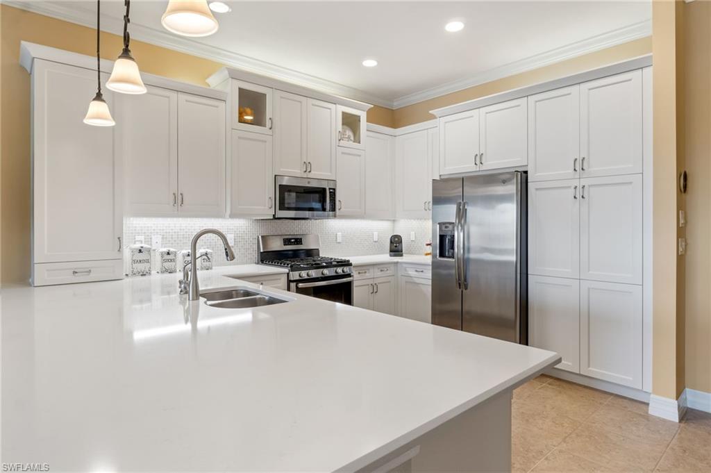 4339 Aurora Street Naples, FL 34119 - Photo 12 of 47 a kitchen with kitchen island a refrigerator sink and stove